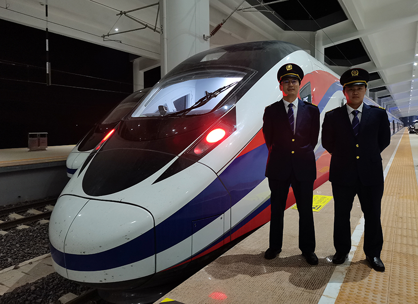 劉銀能（右一）與中國(guó)師父鄔俊鴻在動(dòng)車(chē)組前合影。受訪者供圖